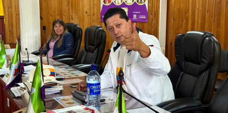 “Edil de Puente Aranda en sesión de la Junta Administradora Local, levantando el pulgar, acompañado por otra edil en la mesa directiva.”