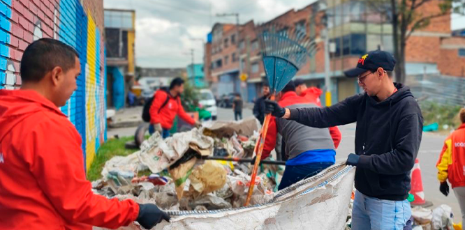 “Alcaldía de Puente Aranda participa en una jornada de limpieza en la calle, retirando basuras y escombros acumulados junto a un muro pintado, en la zona a espaldas de la Cárcel Modelo en Puente Aranda.”