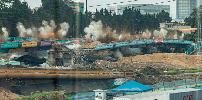 “Implosión controlada de los antiguos puentes vehiculares en la intersección de la Avenida de las Américas con la Calle 13, en Puente Aranda. La imagen muestra el momento del colapso de las estructuras, con columnas de polvo y maquinaria en operación, como parte del proceso de modernización vial de Bogotá.”