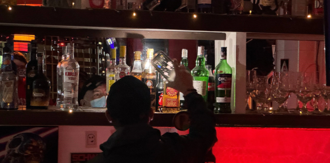 Mientras la ciudad duerme, el compromiso no descansa: operativo nocturno por la seguridad en Puente Aranda Funcionario inspecciona botellas de licor en un bar durante un operativo nocturno de control y seguridad en Puente Aranda.