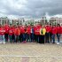 Grupo de gestores locales y funcionarios de la Alcaldía de Puente Aranda, en su mayoría con chaquetas rojas con el logo institucional, posan juntos al aire libre frente a una reja blanca, durante una jornada de capacitación para mejorar la atención integral a habitantes de calle.