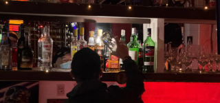 Funcionario inspecciona botellas de licor en un bar durante un operativo nocturno de control y seguridad en Puente Aranda.