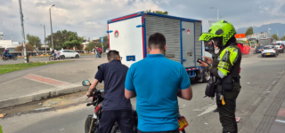 Un agente de tránsito realiza un operativo de control sobre el espacio público, verificando documentos a dos ciudadanos que se movilizaban en una motocicleta, en una vía de Puente Aranda. El procedimiento se desarrolla junto a un camión estacionado y forma parte de las acciones distritales para prevenir el parqueo indebido y recuperar el espacio público.